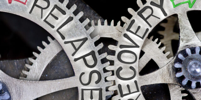 Macro photo of tooth wheel mechanism with imprinted arrows and RELAPSE, RECOVERY concept words